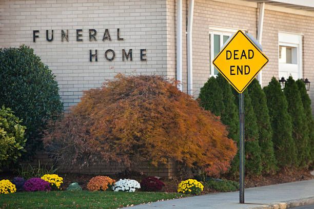 Begravningsbyråfasad med skylten "DEAD END" och höstlövar